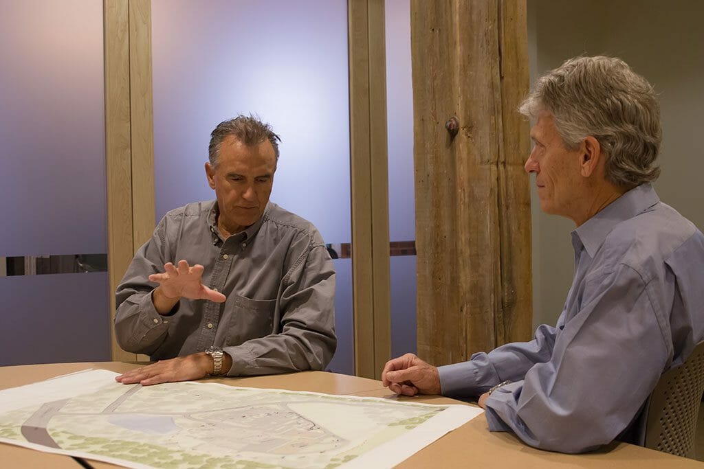 2 men looking at a big map while discussing ideas