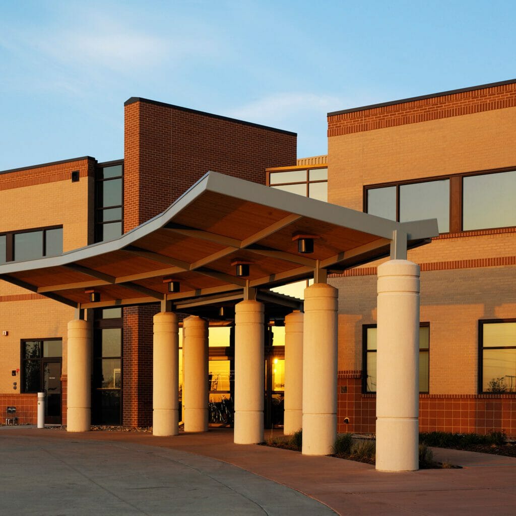 Exterior view of Avista One Medical Plaza with brown and red brick exterior and glass front door with a metal and wood awning over the entrance