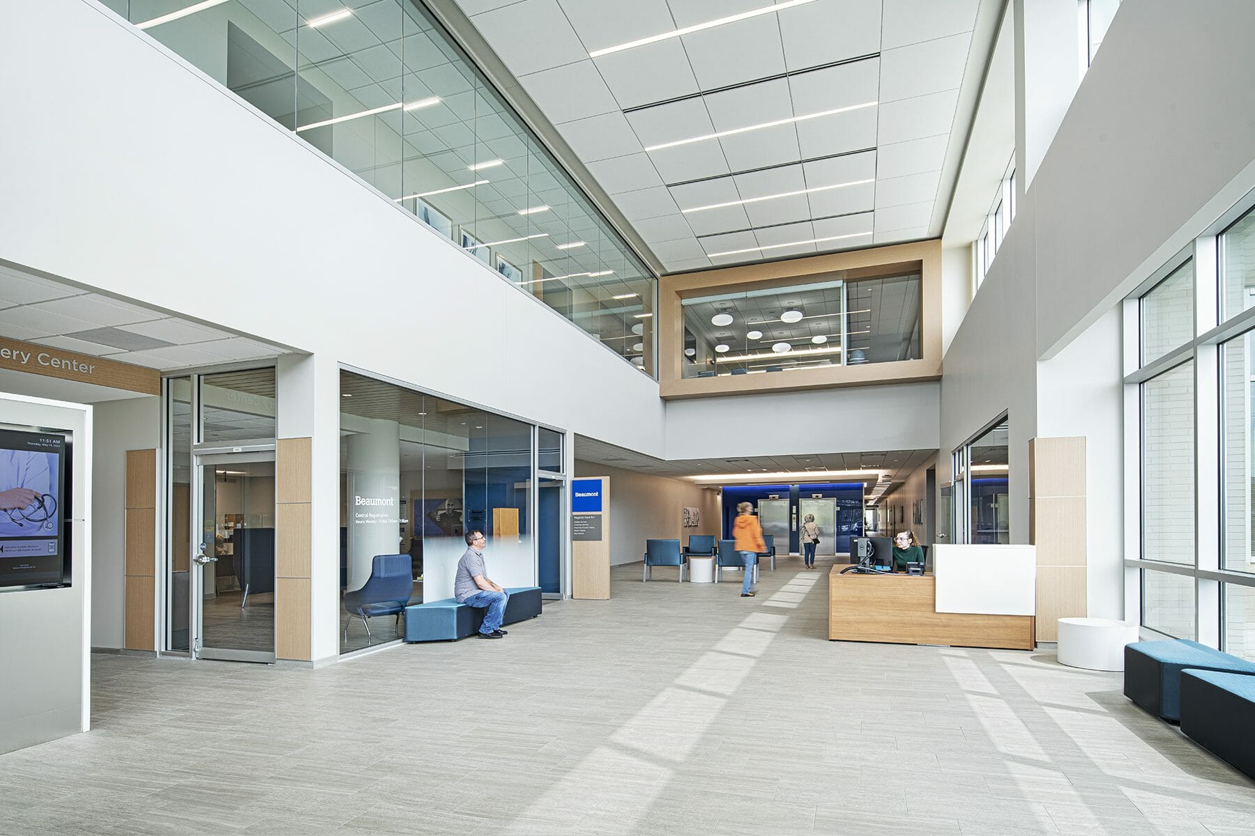 two-story lobby of Beaumont Livonia medical center with gray tiled flors, white walls with tan wood accents.