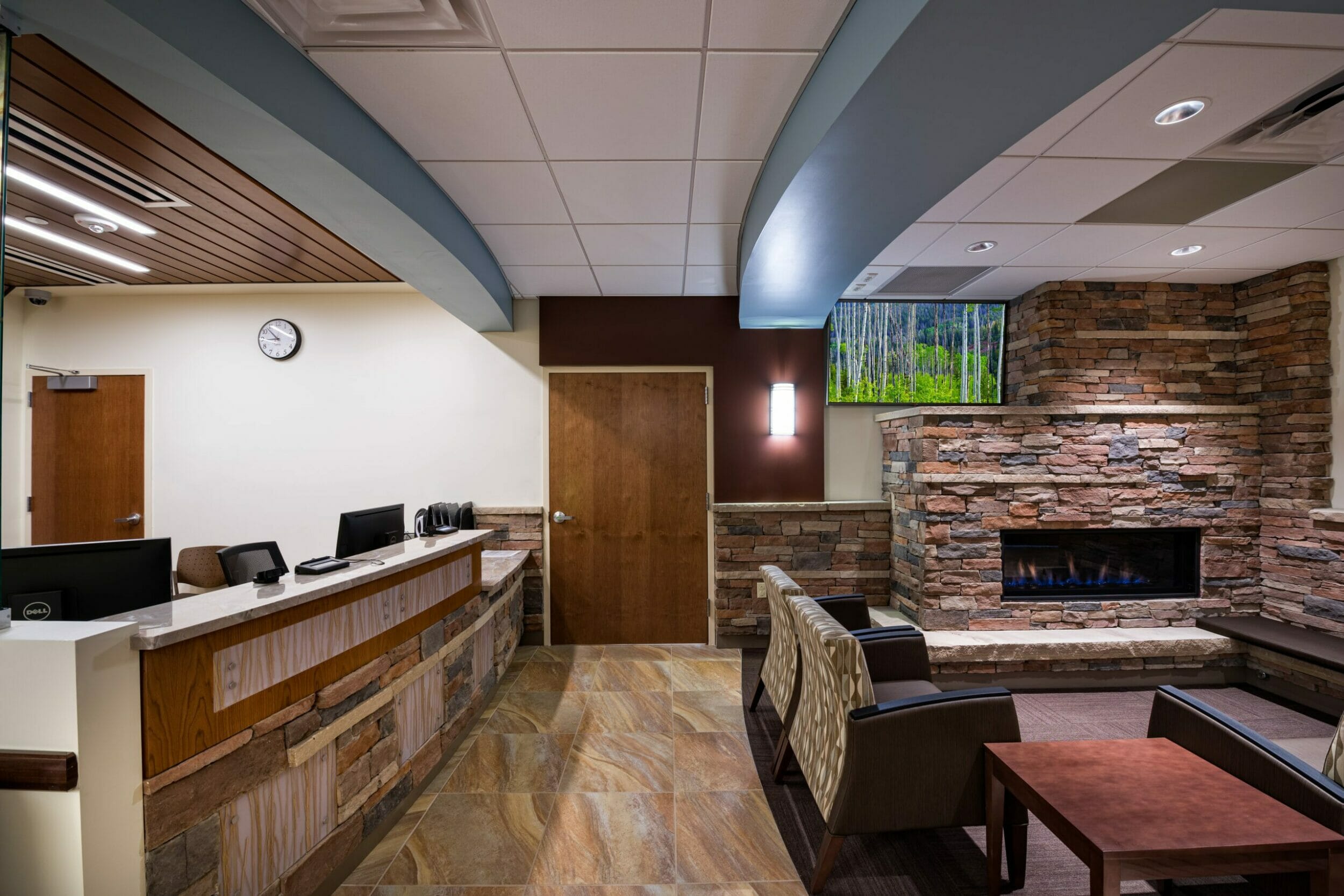 Interior of wood and stone front desk and carpeted lobby with river rock fireplace and tiled floors