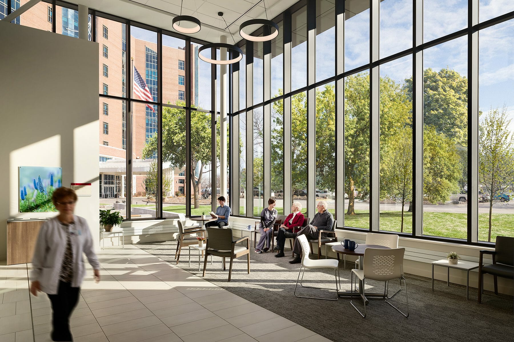 Inside lobby of CHI Cancer Center with all glass walls and people sitting in lobby