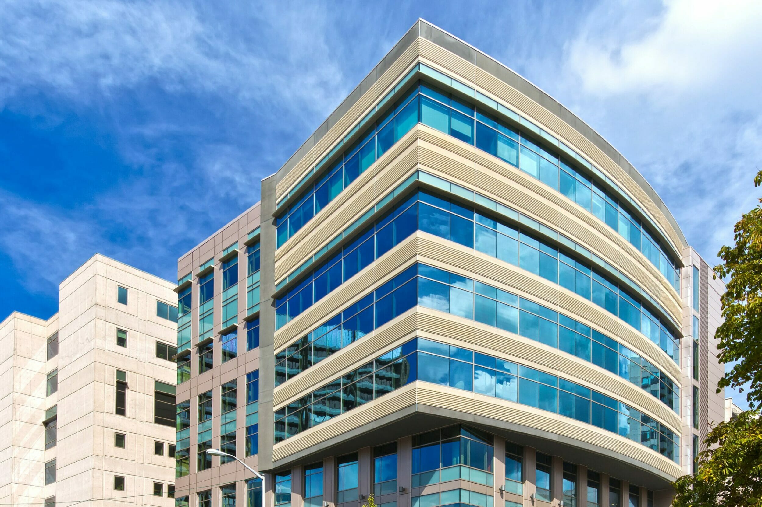 Exterior view large medical pavilion building, windows reflecting blue sky and clouds