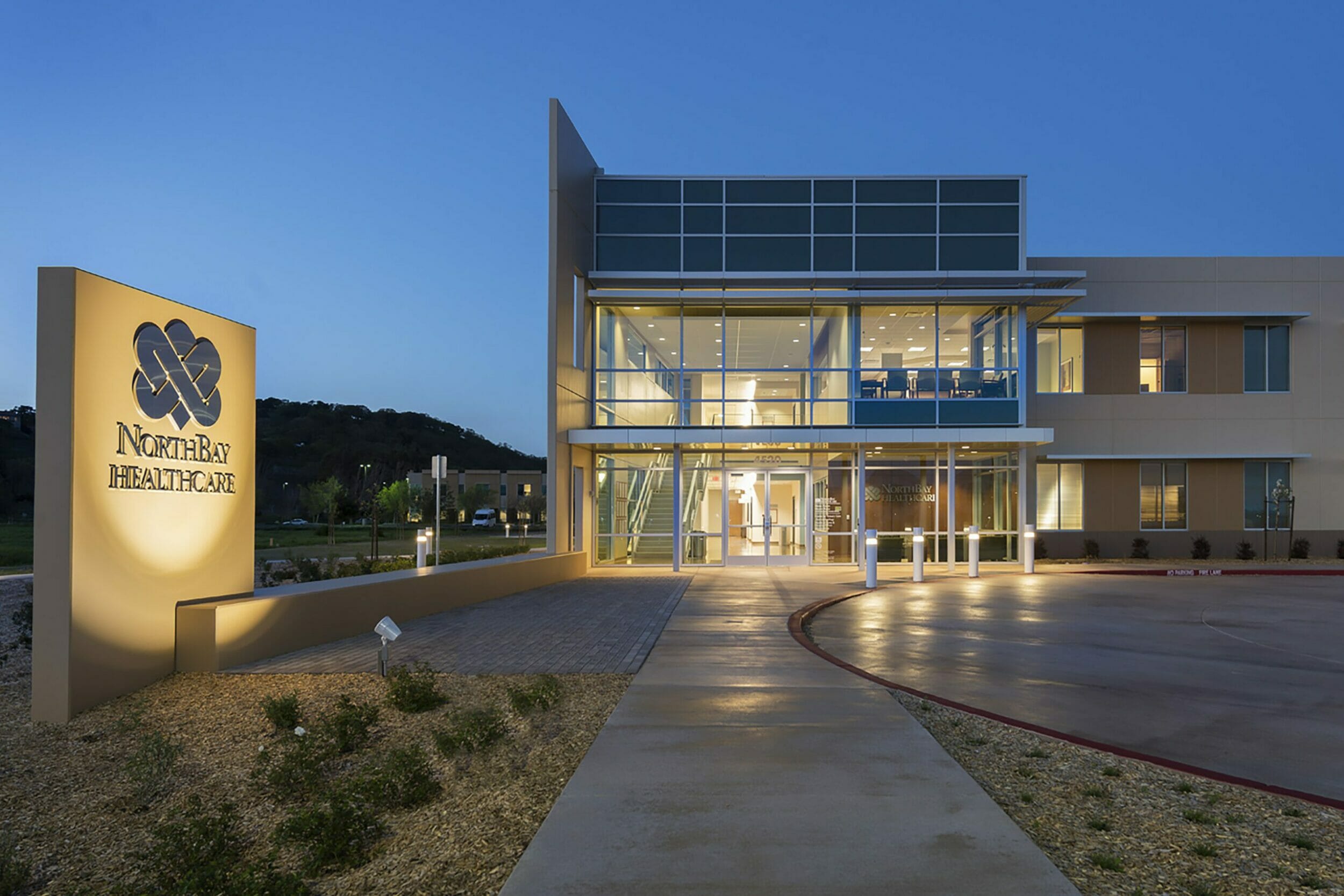 Exterior view of NorthBay Healthcare main entrance at night with lit up sign with company logo