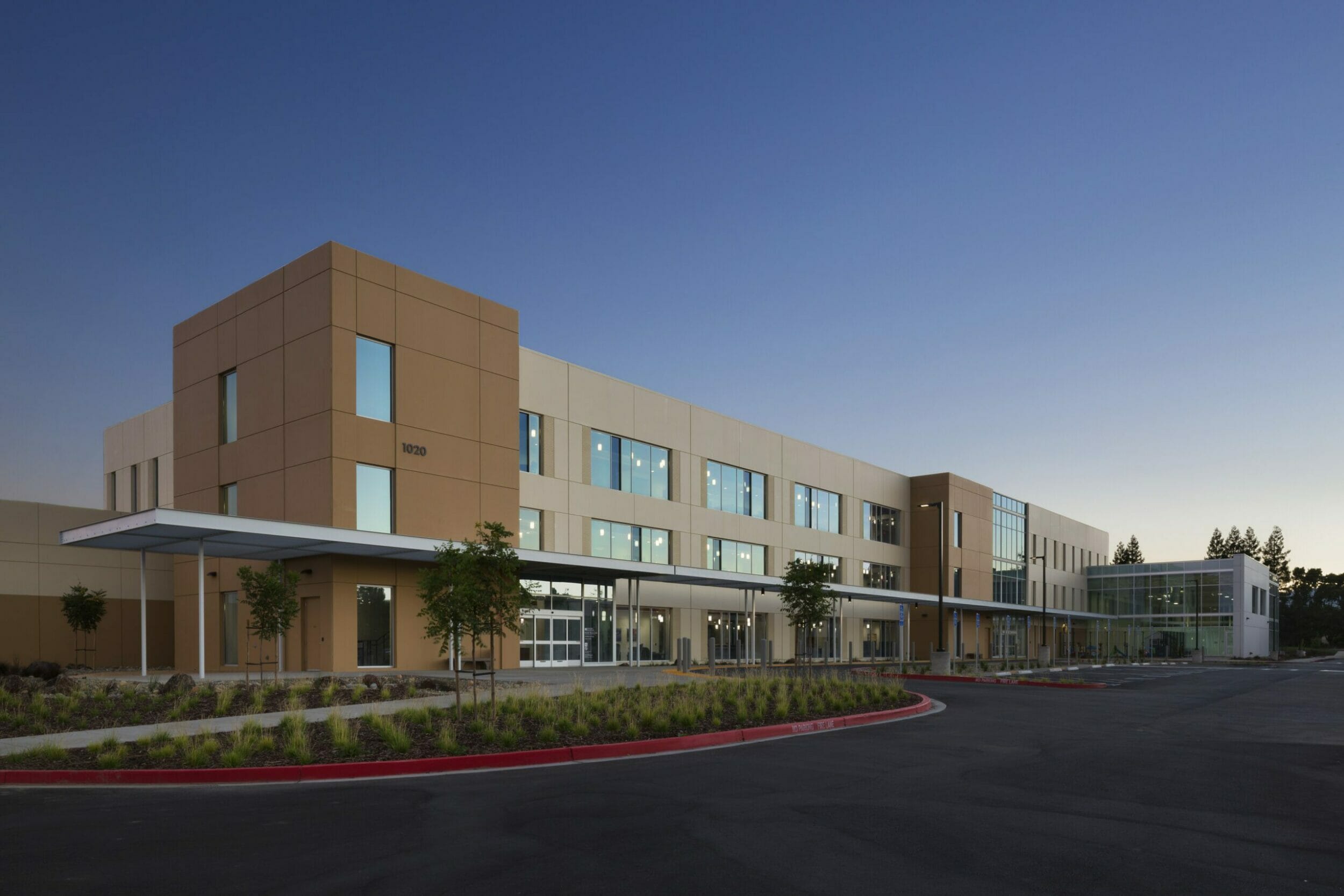 Exterior view of medical building with tan and glass exterior and new plants in the garden