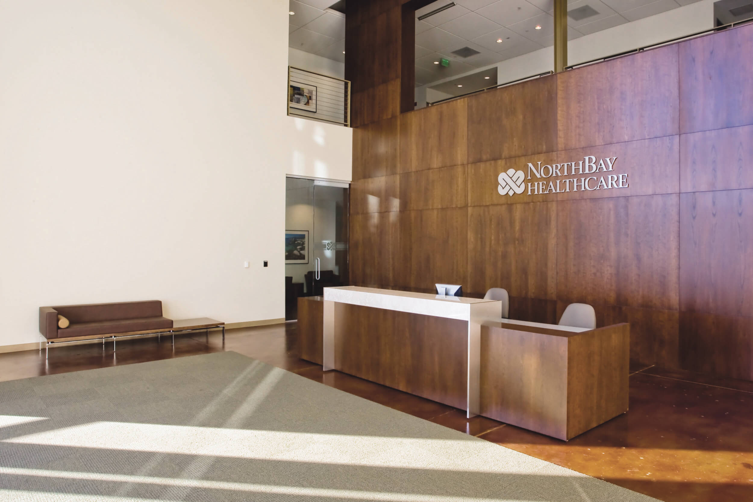 Lobby of NorthBay Healthcare with a wood accent wall and cream walls with a matching wood and cream front desk