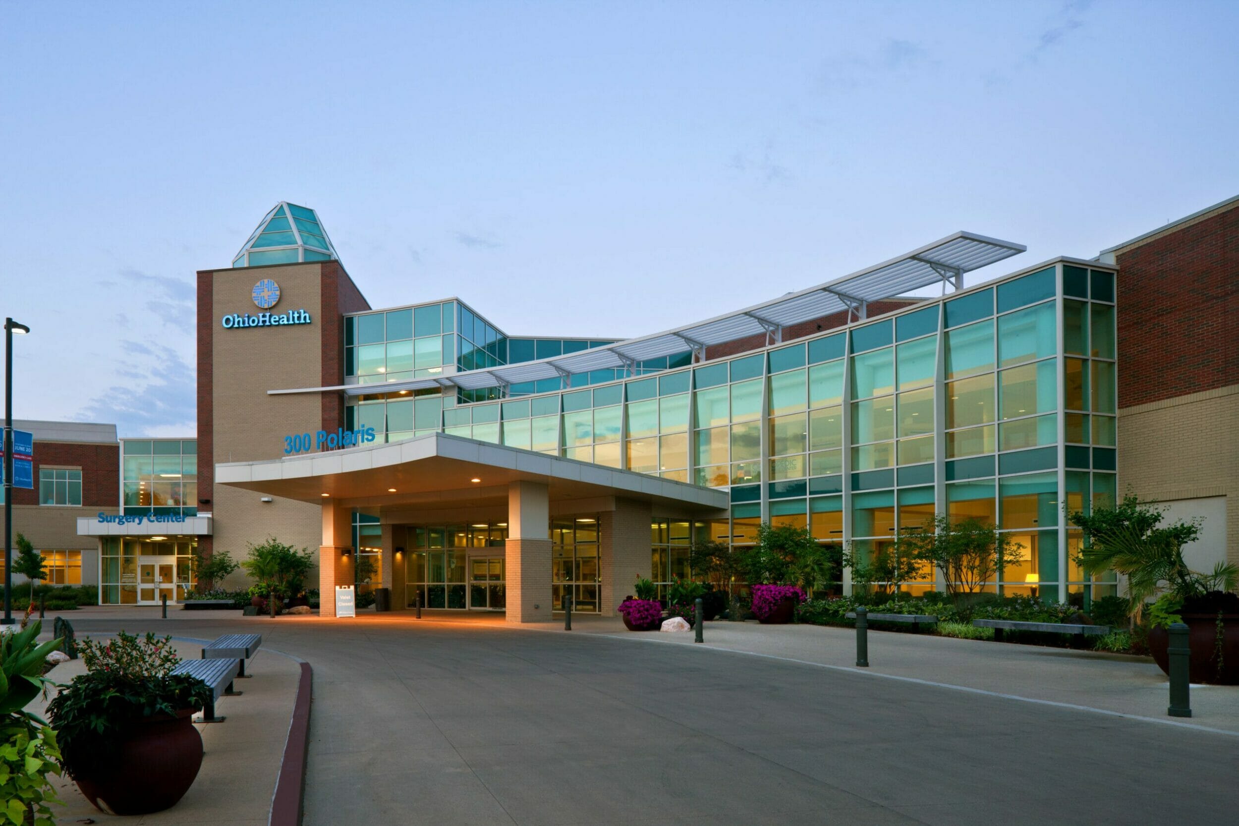 Exterior of Ohio Health Medical Center with large, blue-tinted glass windows behind the porte-cochère with the address on the front