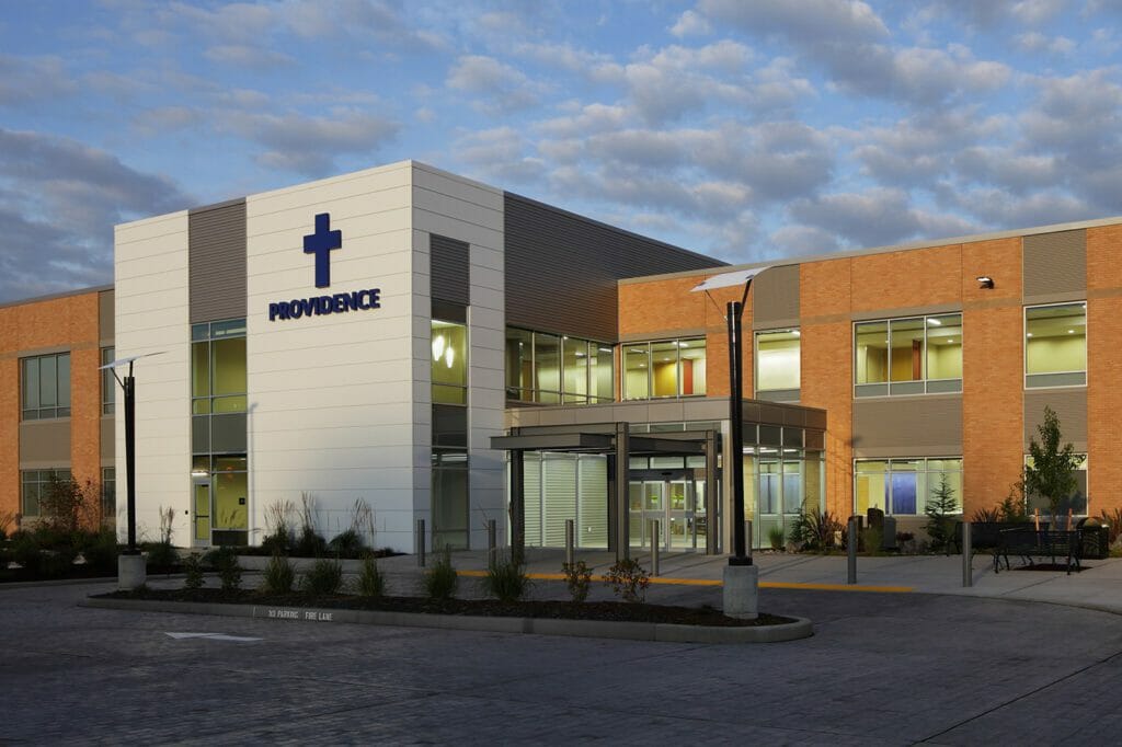 Exterior view of Providence Monroe Family Medicine with a brick exterior and silver and gray accent walls where the blue Providence letters and cross sign are