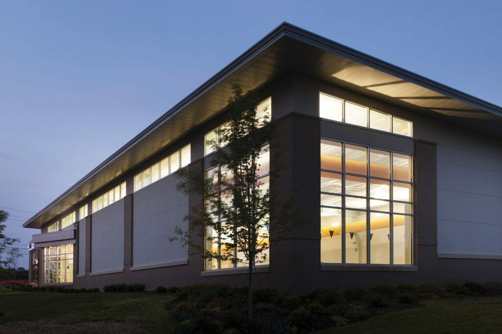 Exterior view of REX wellness center at night with a view of the yellow slide showing from inside the pool area