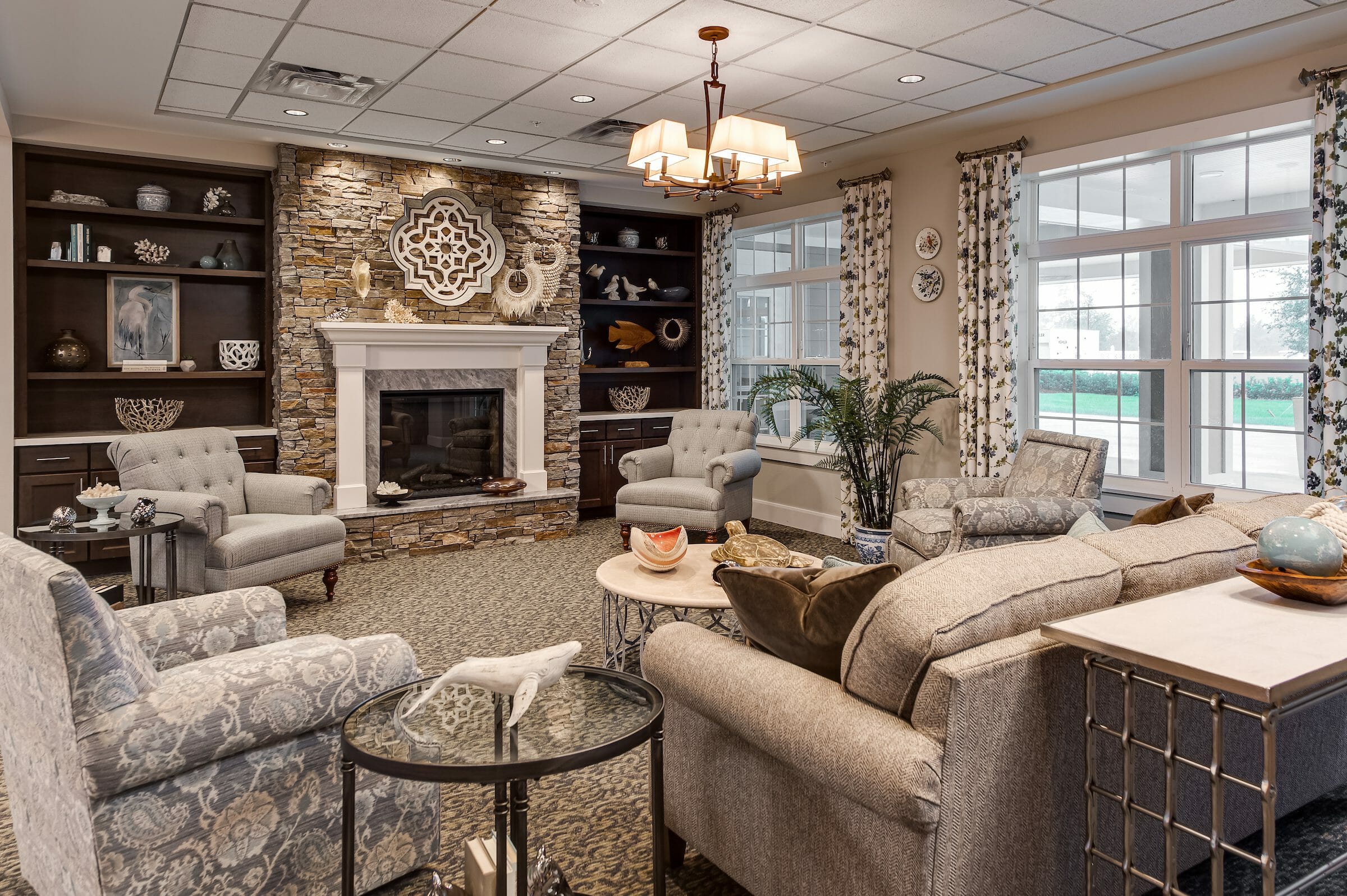 Carpeted living room with stone fireplace and several chairs and a couch