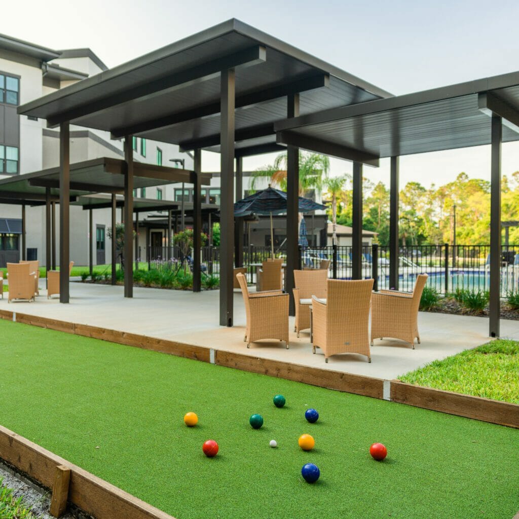 An outdoor bocce ball court with patio furniture in the background