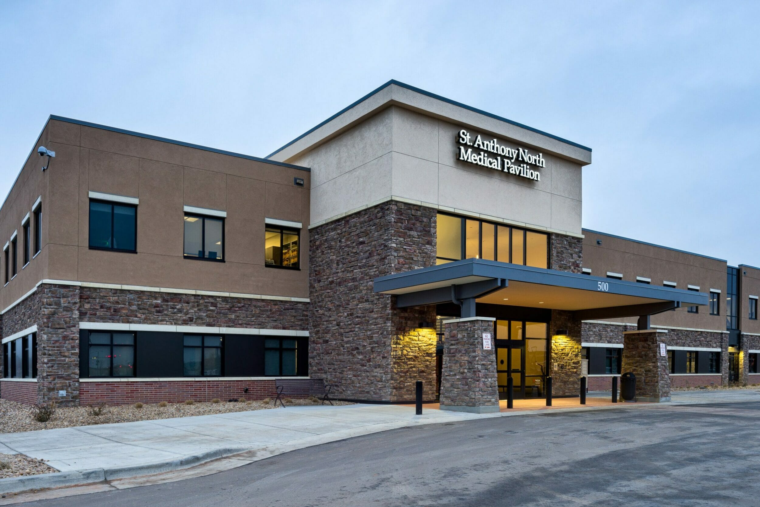 Closeup front view of the front of St. Anthony North Medical Pavillion with stone and stucco exterior with a brick foundation