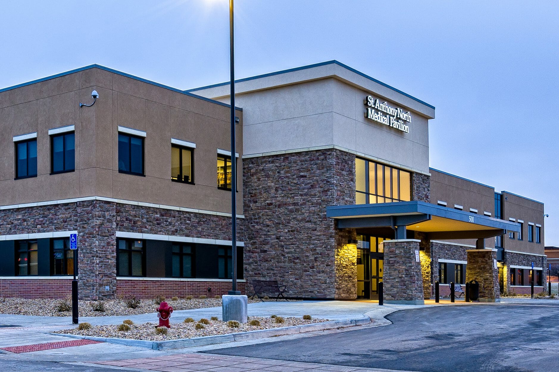 Closeup side angle of the front of St. Anthony North Medical Pavillion with stone and stucco exterior with a brick foundation