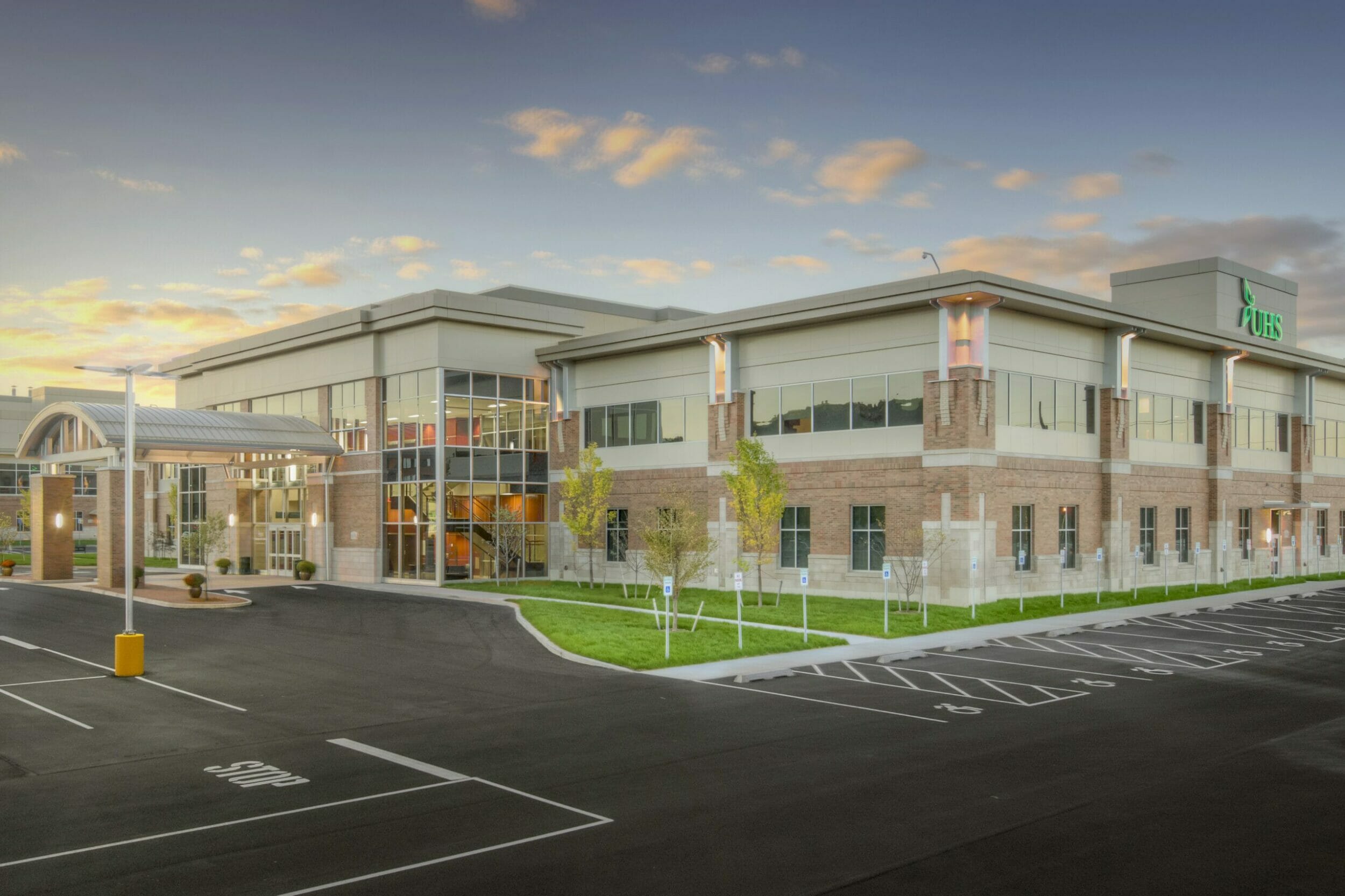 exterior view UHS medical office building. Red brick, tan concrete block building, arched glass window entrance