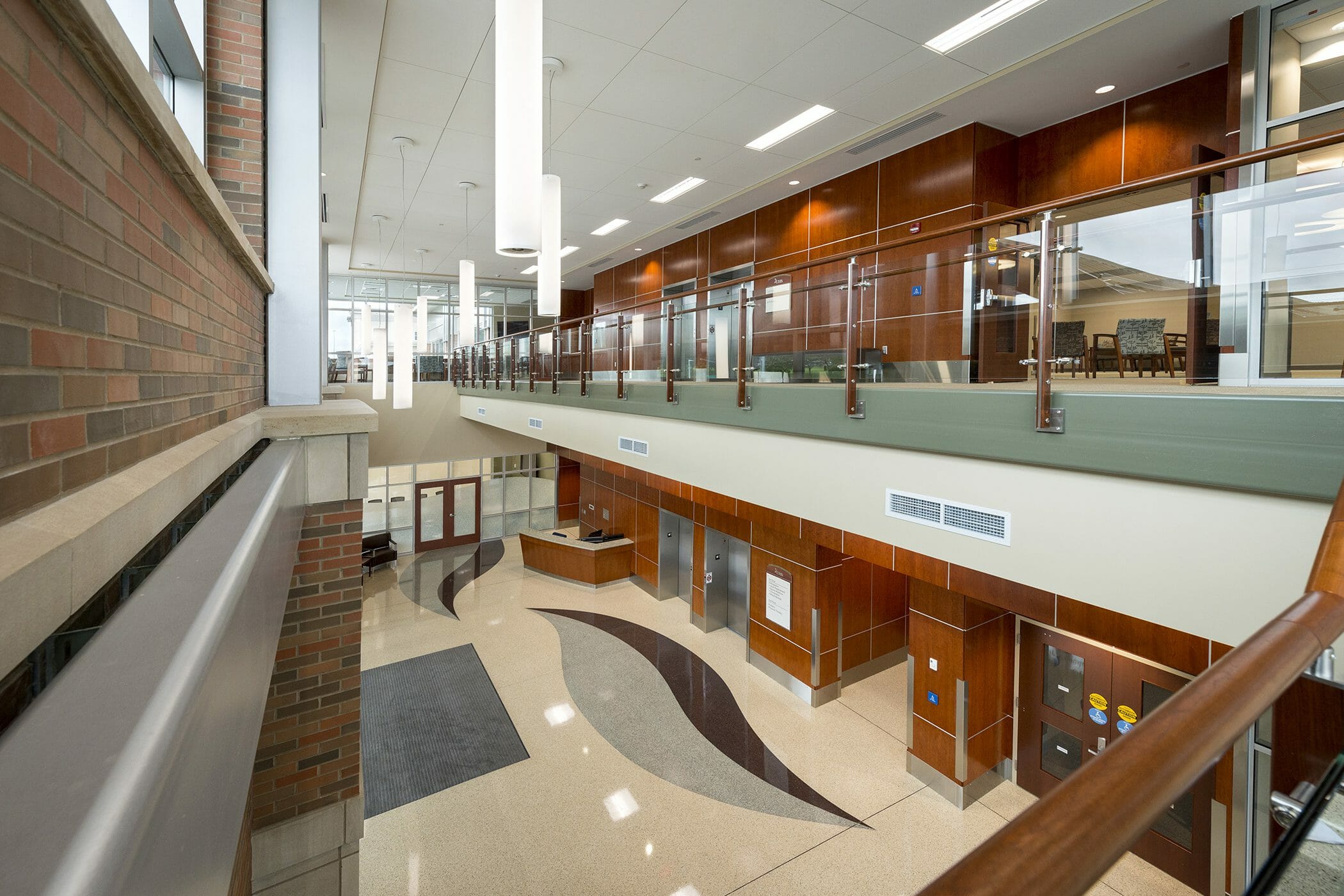 main floor lobby, seating/waiting area , fireplace, staircase to upper level, upper level overlooks main floor with open railing and windowed wall