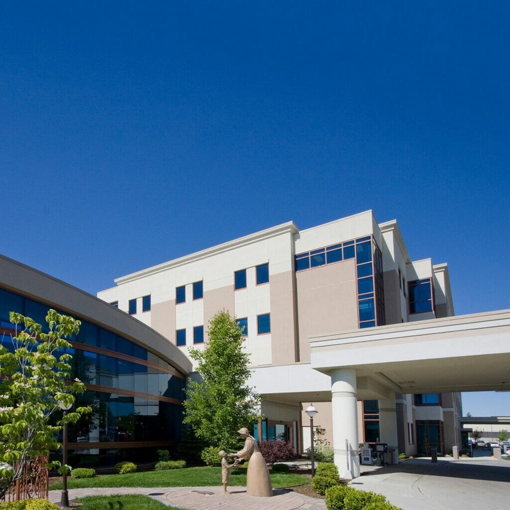 Exterior of Providence Holy Family Hospital Addition and Central Medical Office Building with a statue of a woman helping a child in the foreground